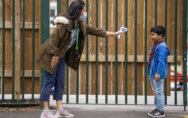 A child has his temperature checked by a teacher before entering Earlham Primary School, which is part of the Eko Trust on June 10, 2020 in London, England. (Photo by Justin Setterfield/Getty Images)